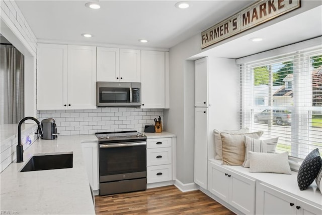 kitchen featuring backsplash, white cabinetry, appliances with stainless steel finishes, and a sink