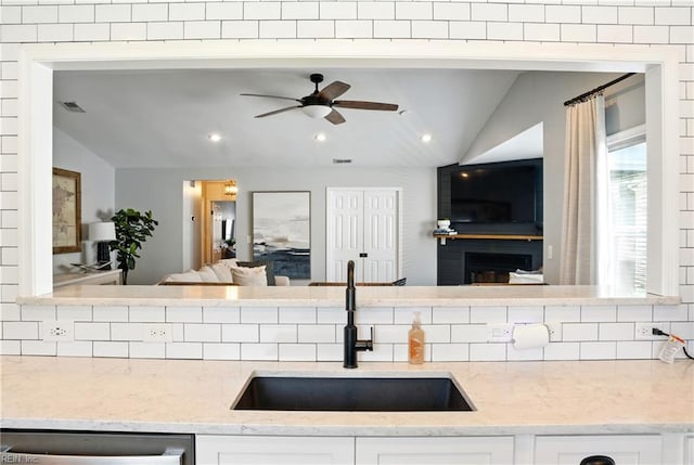 kitchen with a sink, decorative backsplash, lofted ceiling, and open floor plan