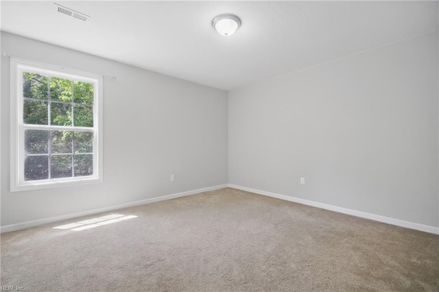 spare room with carpet floors, baseboards, and visible vents