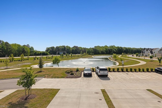 view of home's community featuring a lawn, a water view, and uncovered parking