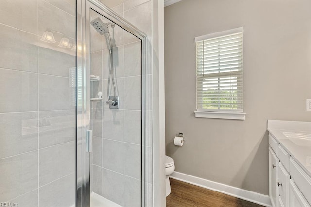 bathroom featuring vanity, toilet, baseboards, a shower stall, and wood finished floors