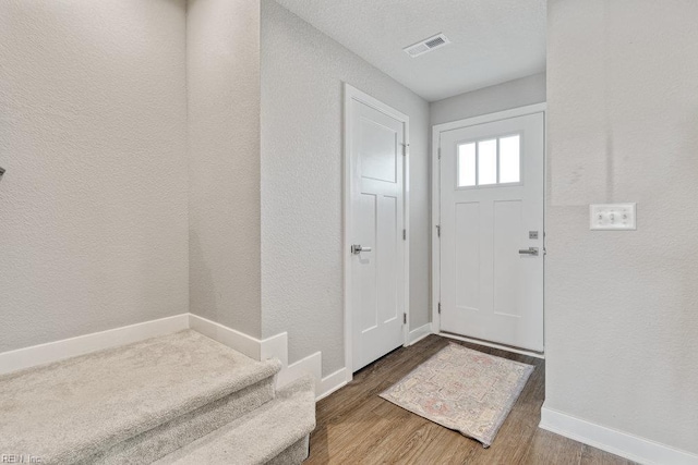 entryway featuring stairway, baseboards, wood finished floors, and visible vents