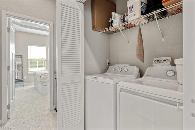 clothes washing area featuring washing machine and clothes dryer, laundry area, light carpet, and baseboards