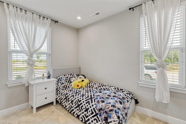 bedroom with visible vents, baseboards, a textured wall, and light carpet