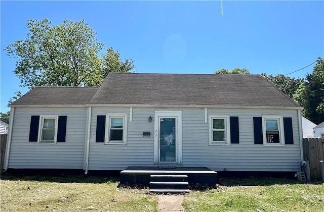 cape cod-style house featuring a front lawn and fence