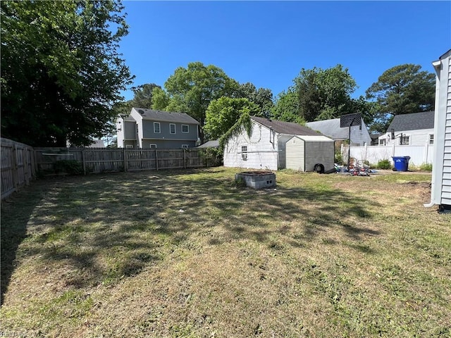 view of yard with a fenced backyard, a storage unit, and an outdoor structure