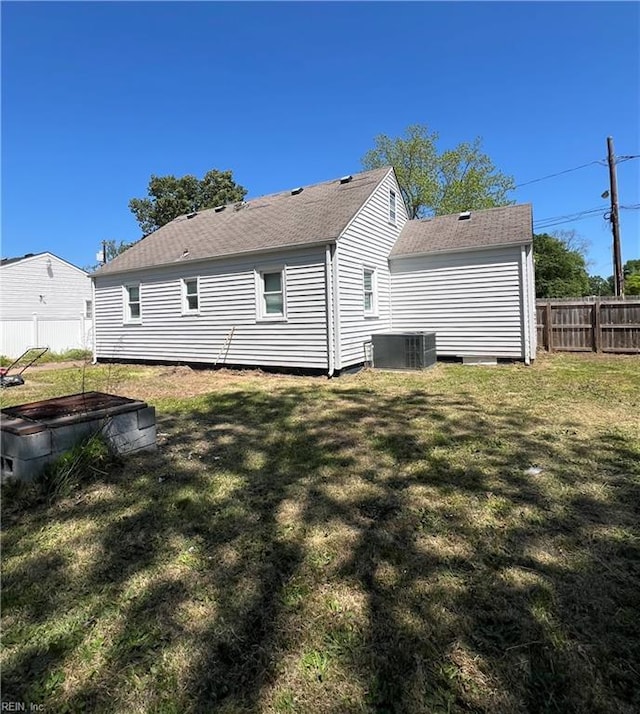 back of property with a lawn, fence, roof with shingles, and cooling unit