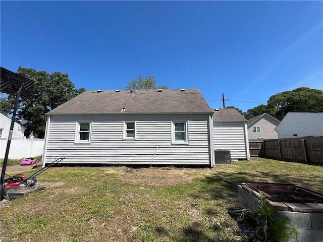 back of property featuring a fenced backyard, a yard, and central AC