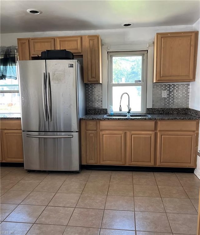 kitchen featuring freestanding refrigerator, a sink, backsplash, and light tile patterned flooring