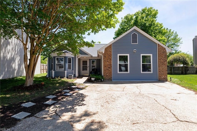 view of front facade featuring fence, aphalt driveway, a front lawn, and brick siding