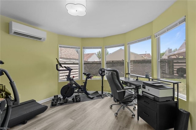 home office featuring plenty of natural light, baseboards, a wall unit AC, and wood finished floors