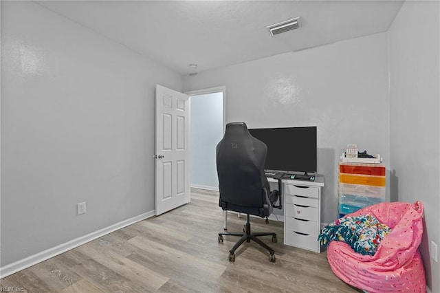 home office with baseboards, wood finished floors, and visible vents