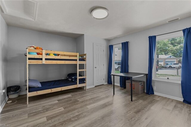bedroom with baseboards, attic access, wood finished floors, and visible vents