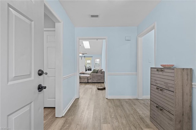 hallway featuring baseboards, wood finished floors, and visible vents