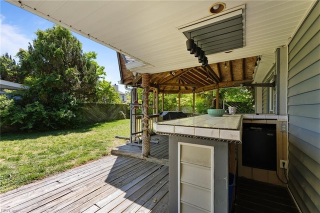 wooden terrace with a lawn, a fenced backyard, and outdoor dry bar