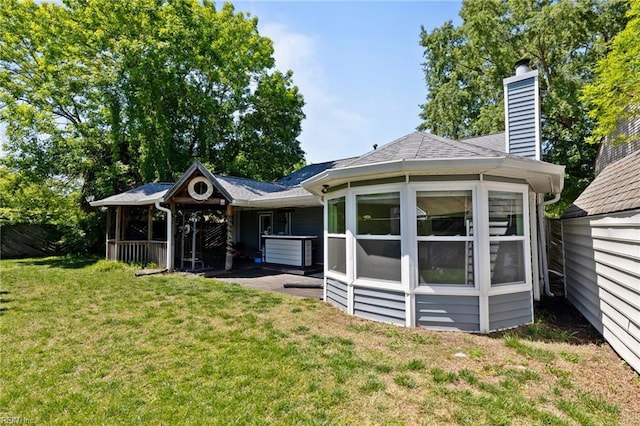 rear view of property featuring a lawn, roof with shingles, and a chimney