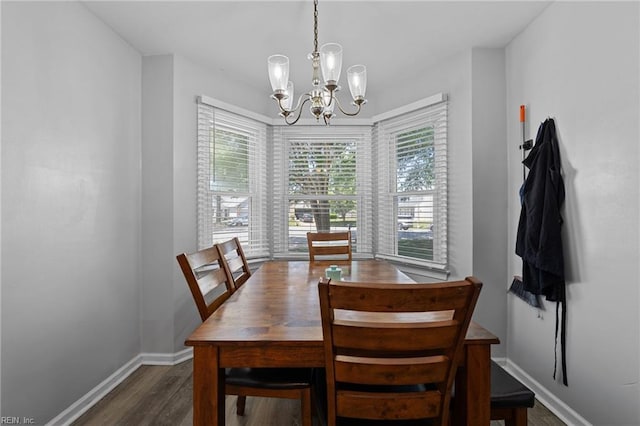 dining area featuring baseboards, dark wood finished floors, and a chandelier
