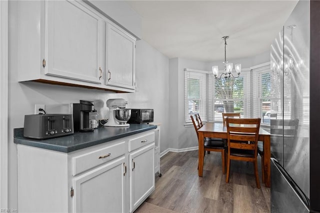 dining space with baseboards, a chandelier, and wood finished floors