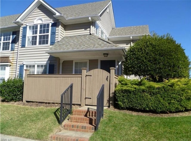 view of front of home featuring roof with shingles, fence, and a front yard