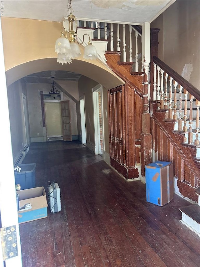 entrance foyer featuring arched walkways, hardwood / wood-style flooring, a chandelier, and stairs