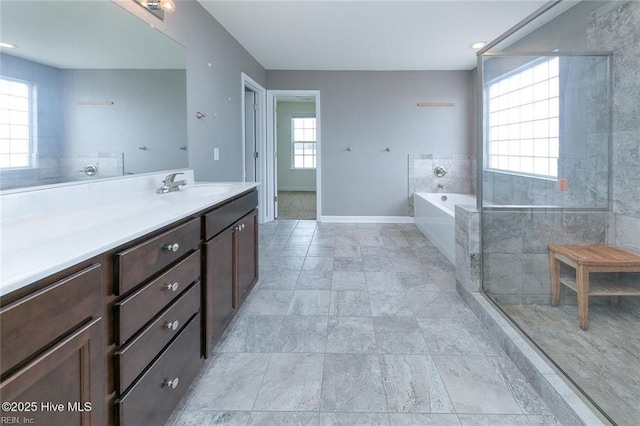 full bathroom featuring vanity, baseboards, a garden tub, and stone finish flooring