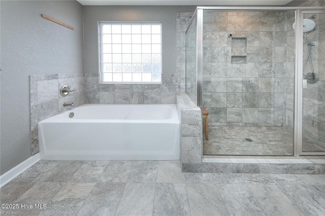 full bath featuring a textured wall, a stall shower, and a bath