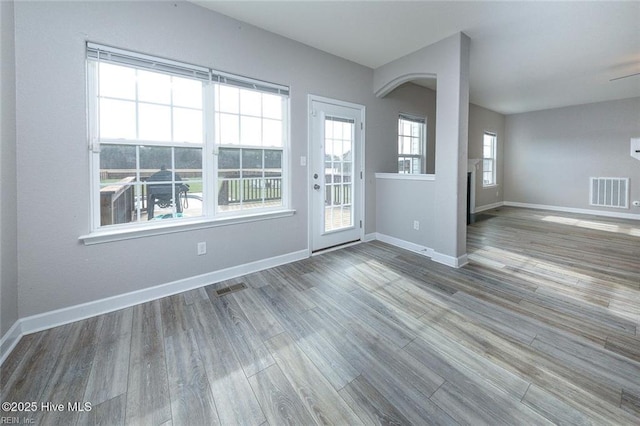 spare room featuring baseboards, visible vents, and wood finished floors