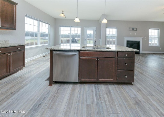 kitchen featuring a sink, light wood-style flooring, baseboards, open floor plan, and stainless steel dishwasher