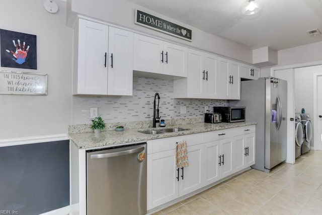 kitchen featuring separate washer and dryer, a sink, white cabinetry, and appliances with stainless steel finishes