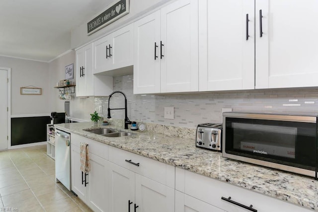 kitchen featuring decorative backsplash, a sink, light tile patterned floors, white cabinets, and stainless steel appliances