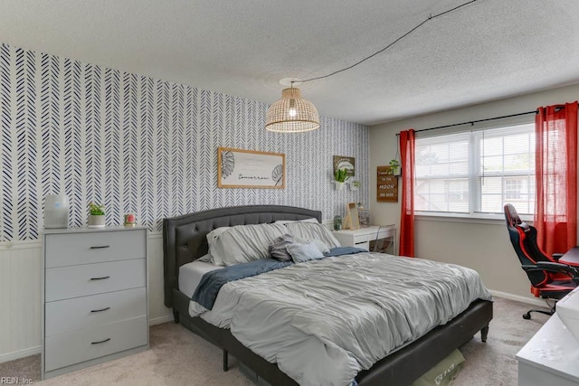 bedroom with a textured ceiling, wallpapered walls, light colored carpet, and baseboards