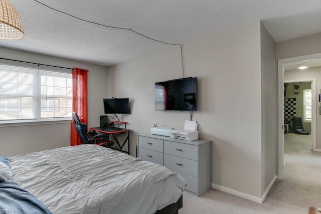 bedroom with light colored carpet, a textured ceiling, and baseboards