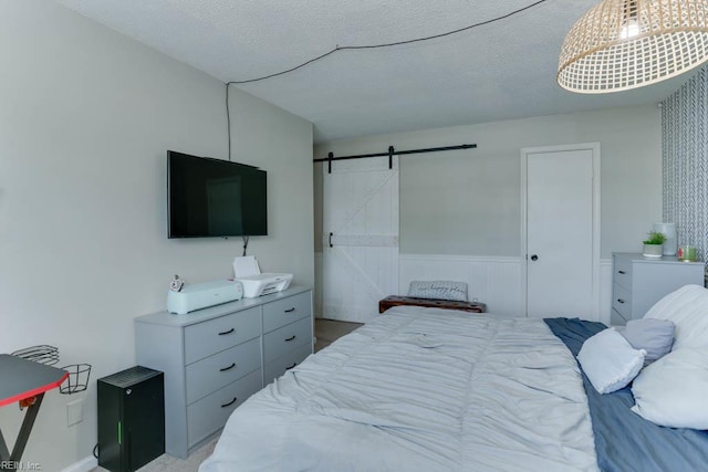 bedroom with wainscoting and a barn door