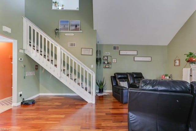 living area featuring baseboards, visible vents, wood finished floors, and stairway