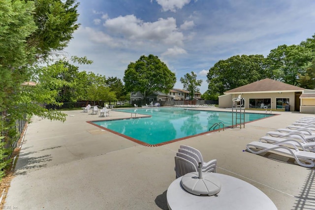 community pool with fence and a patio area
