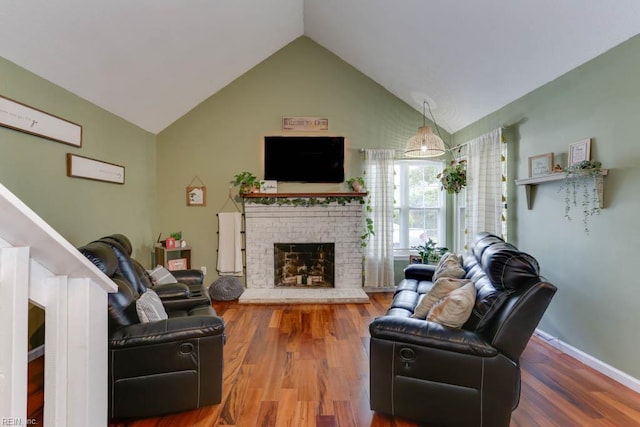 living room with wood finished floors, a brick fireplace, and lofted ceiling