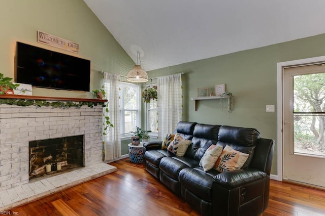 living area featuring baseboards, a brick fireplace, hardwood / wood-style flooring, and high vaulted ceiling
