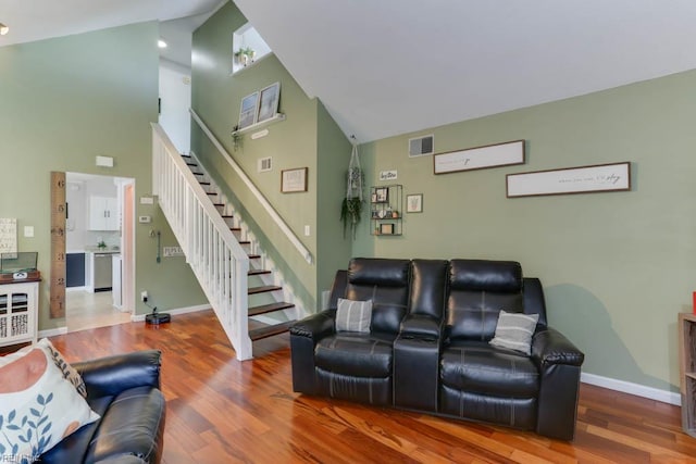 living room with baseboards, high vaulted ceiling, wood finished floors, and stairway