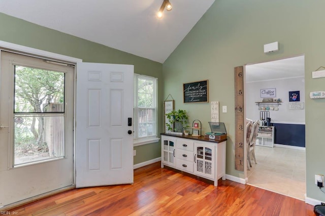 foyer entrance with baseboards, light wood finished floors, a healthy amount of sunlight, and high vaulted ceiling