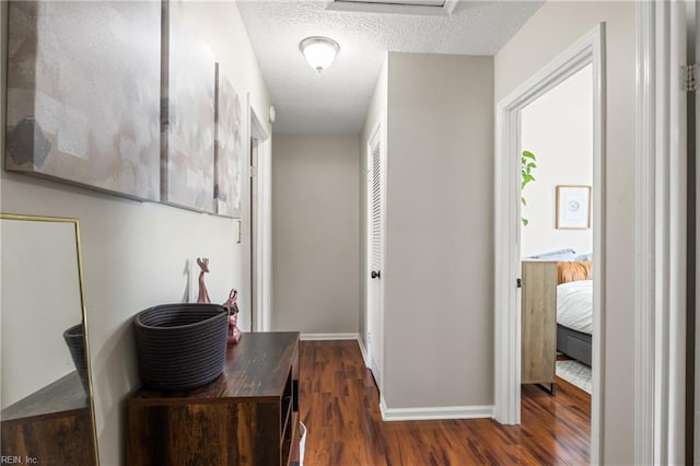 hall featuring baseboards, a textured ceiling, and wood finished floors
