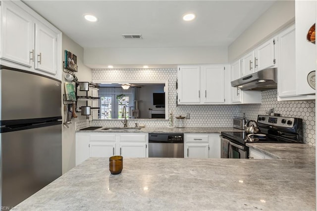 kitchen featuring visible vents, under cabinet range hood, tasteful backsplash, a sink, and appliances with stainless steel finishes