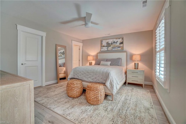 bedroom featuring baseboards, ceiling fan, wood finished floors, and visible vents
