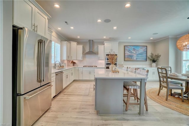 kitchen with crown molding, a sink, wall chimney exhaust hood, and stainless steel appliances