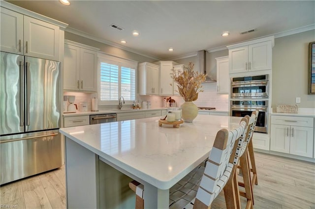 kitchen with crown molding, a kitchen island, light wood-style floors, tasteful backsplash, and appliances with stainless steel finishes