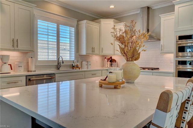 kitchen with decorative backsplash, ornamental molding, wall chimney exhaust hood, a sink, and stainless steel appliances