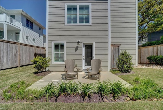 back of property featuring a lawn, a patio area, and fence