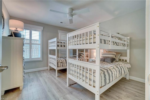 bedroom featuring a ceiling fan, baseboards, visible vents, and wood finished floors