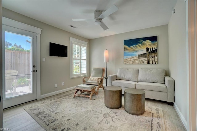 living area with light wood-type flooring, a ceiling fan, and a wealth of natural light