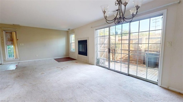 unfurnished living room with a chandelier, carpet, and baseboards