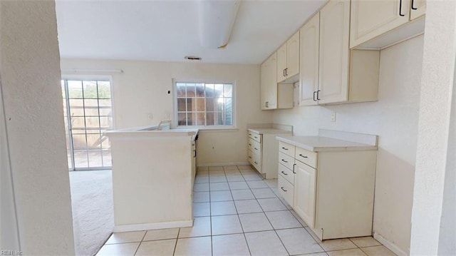 kitchen with light tile patterned flooring, baseboards, light countertops, and a textured wall